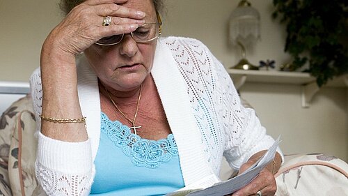 Woman looking concerned while reading a piece of paper