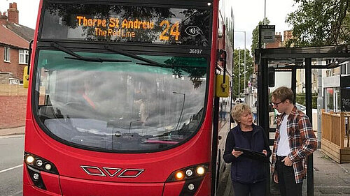 Cllr Lubbock and JH in front of a red bus in Norwich.