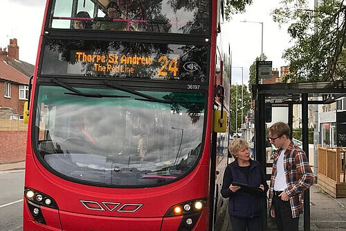 Cllr Lubbock and JH in front of a red bus in Norwich.